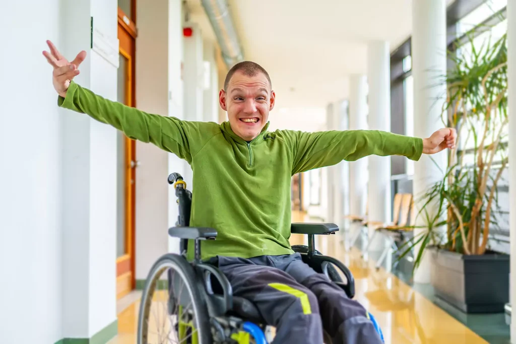 A young disabled man is smiling and excited while sitting in his wheelchair